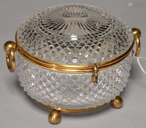 A GILTMETAL MOUNTED CUT GLASS CASKET, C1890, WITH RING HANDLES, ON BALL FEET, 14CM DIAM Good