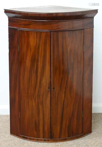 A GEORGE III BOW FRONTED MAHOGANY HANGING CORNER CUPBOARD, EARLY 19TH C, WITH FLARED CORNICE AND