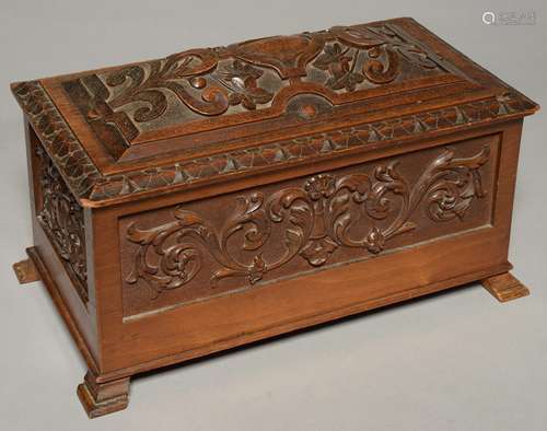 AN EDWARDIAN CARVED WALNUT CASKET AND COVER, C1900, DECORATED WITH FOLIAGE AND STRAPWORK, 39CM L