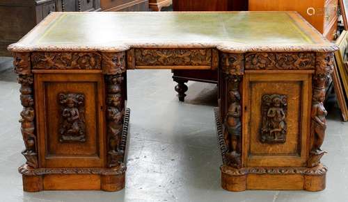 A VICTORIAN CARVED AND PANELLED OAK BREAKFRONT PEDESTAL DESK WITH GREEN TOOLED LEATHER INLET TOP,