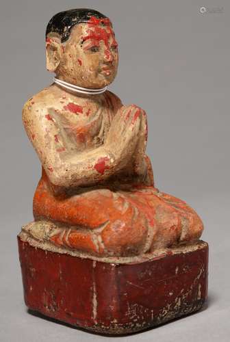 A SOUTH EAST ASIAN POLYCHROME WOOD SCULPTURE OF A KNEELING DEVOTEE, ON OBLONG RED BASE, 14CM H Paint