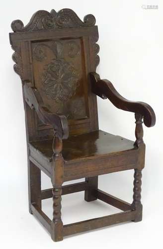 A 17thC oak Wainscot chair with a scrolled and carved cresting rail above a highly decorative and