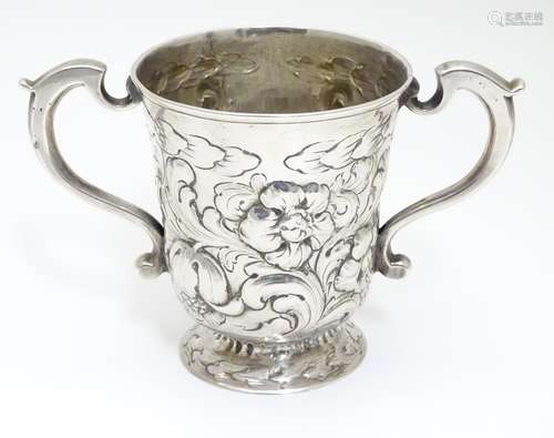 A silver mug of loving cup form with embossed decoration. Hallmarked Newcastle 1760-1768 maker