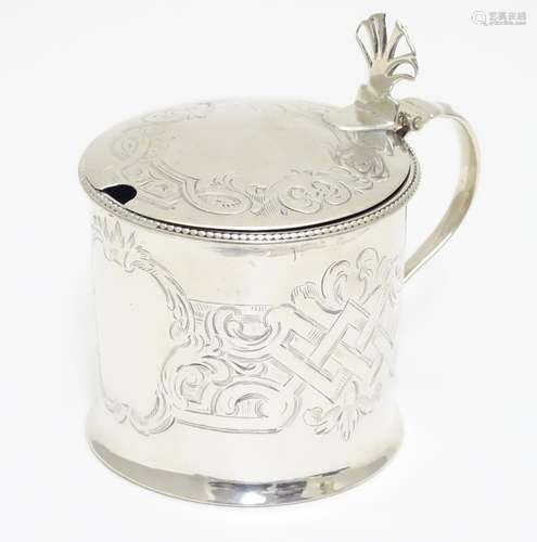 A sliver mustard pot with engraved decoration, hinged lid and blue glass liner. Hallmarked London