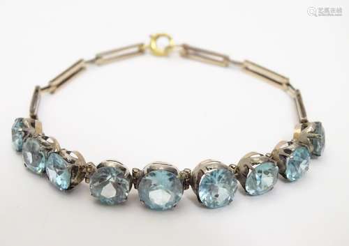 An early 20thC 9ct gold bracelet set with 9 blue zircon. Please Note - we do not make reference to