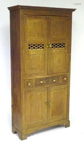 An early 19thC oak Welsh bread and cheese cupboard with a moulded cornice above quarter sawn oak