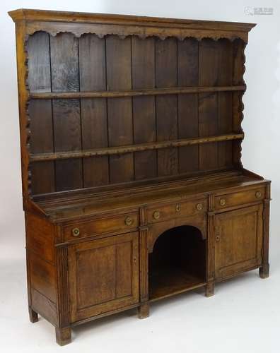 An 18thC oak dresser with a moulded cornice above a shaped frieze and two shelves. The base