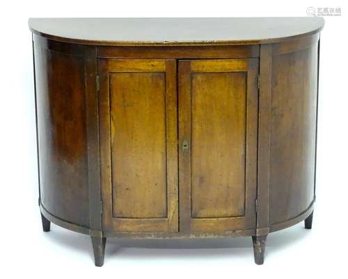 An 18thC mahogany demi lune commode with two panelled doors opening to show adjustable shelve