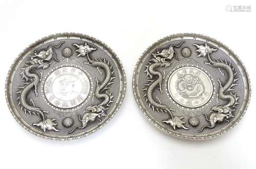 Two white metal dishes with dragon decoration one set with a Republic of China one dollar coin/