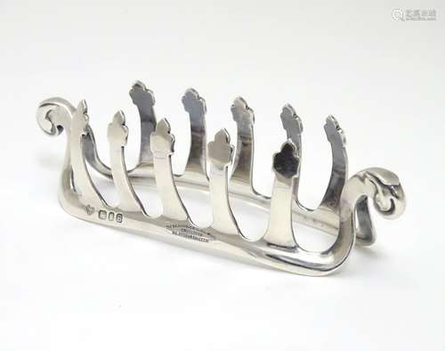 A silver toast / letter rack with shaped bars and scroll ends. Hallmarked London 1937 maker