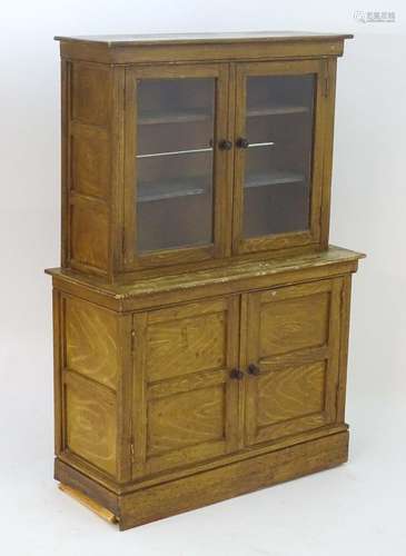 An early / mid 20thC scumbled bookcase with a moulded cornice above two glazed doors opening to show