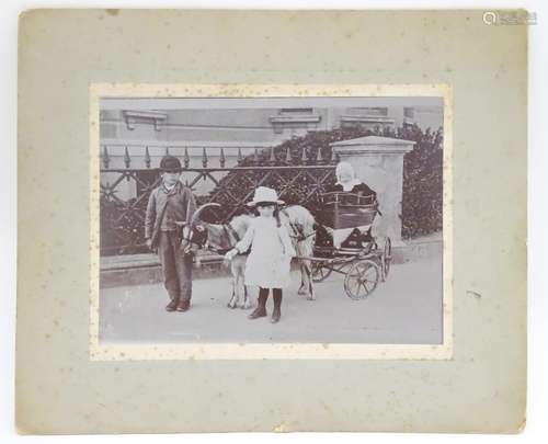 A Victorian monochrome photograph, depicting two children leading a goat pulling a small