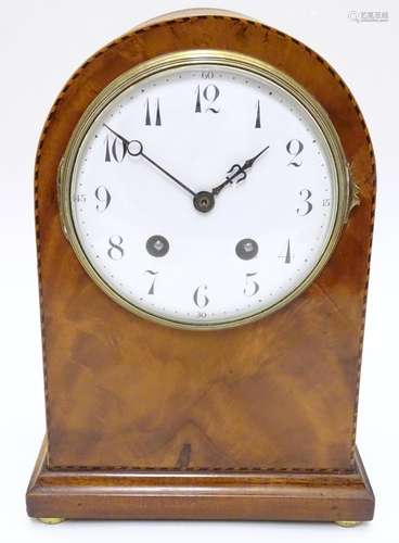 A 19thC arch top mantel clock, the flame mahogany case with boxwood and ebony stringing, enamelled