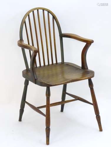 A late 18thC / early 19thC Windsor chair with a bowed back, swept arms, saddle seat and raised on