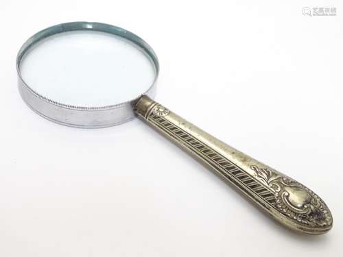 White metal mounted magnifying glass. Glass approx. 2 ½? diameter, approx. 6? long overall. Please