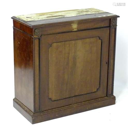 A Regency mahogany cupboard with applied roundel decorations and having a single panelled door above