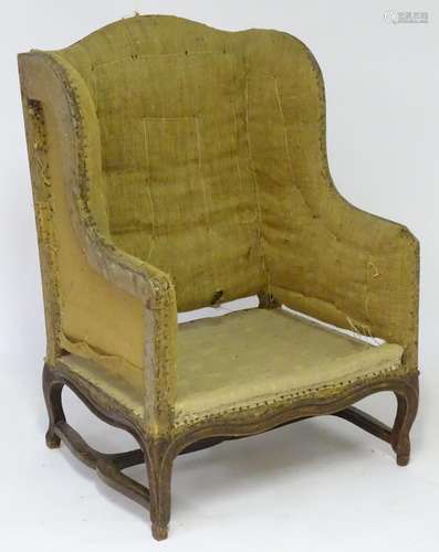 An 18thC French Louis XV wingback armchair, with a shaped top and sides, a walnut frame with moulded