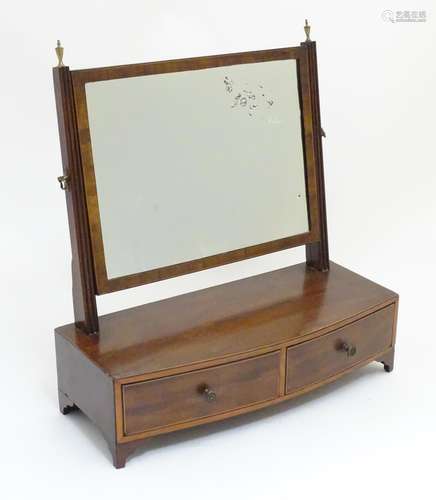 A 19thC mahogany toilet mirror with a rectangular adjustable mirror and mounted by brass finials.