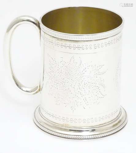 A Victorian silver mug with engraved decoration and loop handle. Hallmarked London 1872 maker