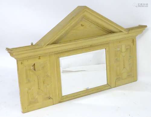 An early 20thC pine overmantel mirror with a pointed pediment above a dentil carved frieze and