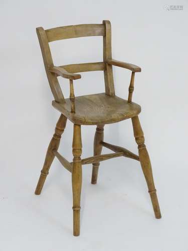 A Victorian childs chair with swept arms, turned supports and having an elm seat. Standing on turned