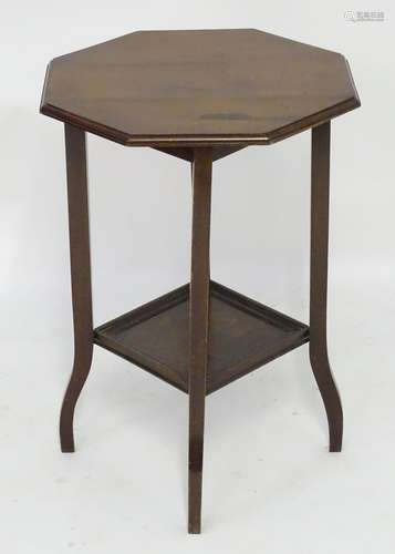 An early 20thC walnut occasional table with an octagonal top above a squared under tier and standing