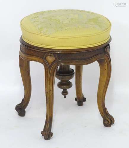 A late 19thc walnut adjustable piano stool, with a rotating upholstered seat above a carved frame