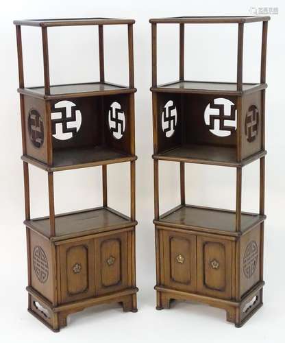 A pair of Chinese bookcases with four tiers supported by turned columns and having panelled cupboard