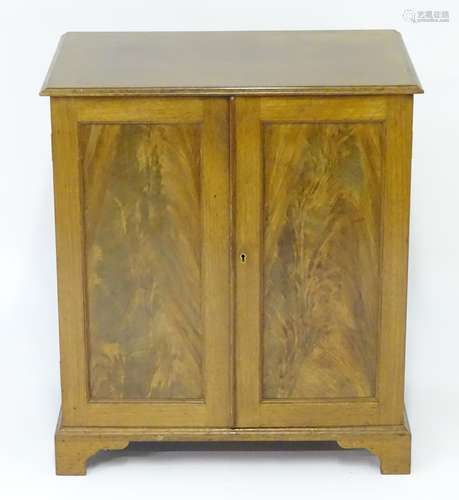 An early 20thC mahogany cabinet with a moulded top above two panelled doors opening to show