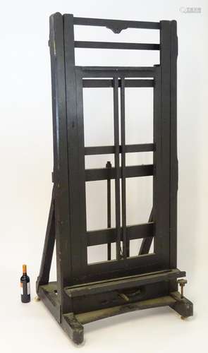 A late 19thC ebonised easel of large proportions , having a chamfered frame and moving on ceramic