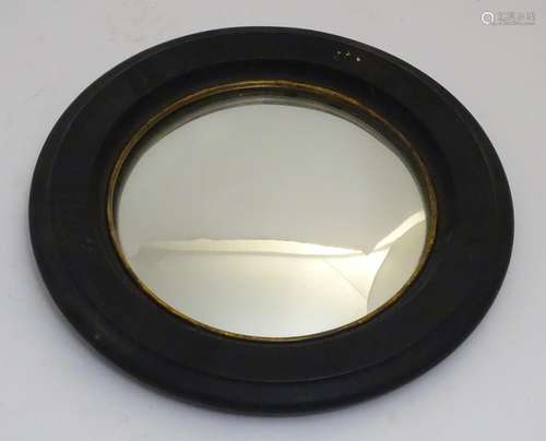 A 19thC convex mirror with an ebonised surround and giltwood lining. 16