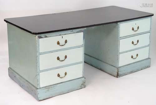 An early 20thC double pedestal desk with a large ebonised top above two banks of three short drawers