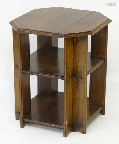 An early 20thC oak bookcase with an octagonal top above two lower tiers and having applied roundel