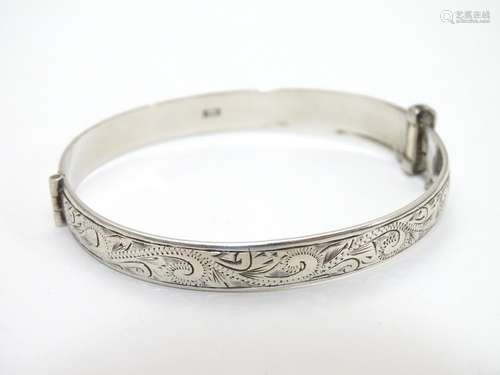 A silver bracelet of bangle form with engraved decoration Hallmarked Birmingham 1975 maker Henry