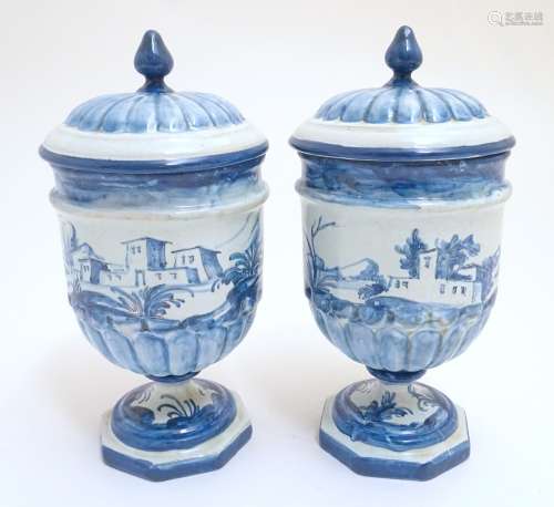 A pair of Continental blue and white pedestal jars and covers decorated with hand painted
