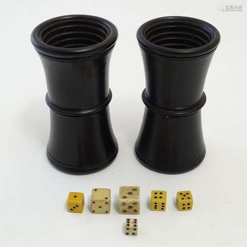 Toys: A pair of treen 19thC waisted ebonised wooden dice shakers with horizontal ribbed interiors