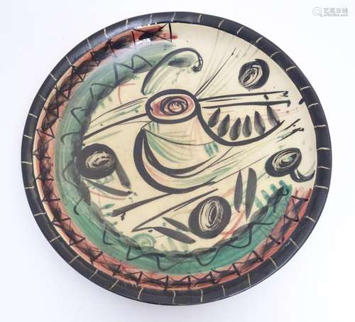 A 20thC studio pottery charger with hand painted abstract decoration. Marked to base Manasseh NP