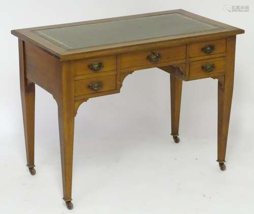 An early 20thC Arts & Crafts style walnut desk with a gold tooled leather top above a five drawer