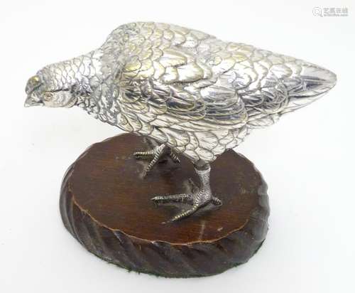 A cast silver plate model of a hen / chicken mounted on a wooden base. The whole 5