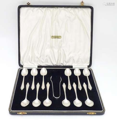 A cased set of 12 silver coffee spoons with tongs ensuite. Hallmarked Birmingham 1936 (tongs) and