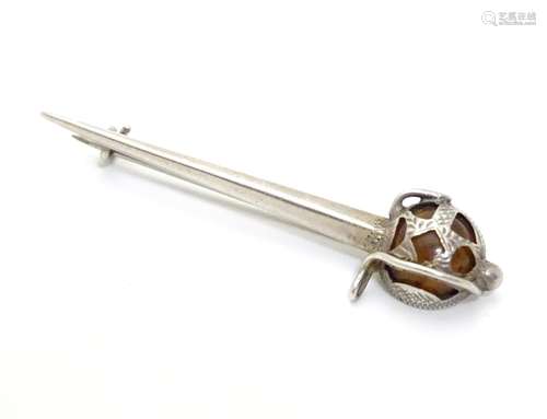 A silver brooch formed as a sword the basket hilt set with amber coloured stone. Marked Sterling