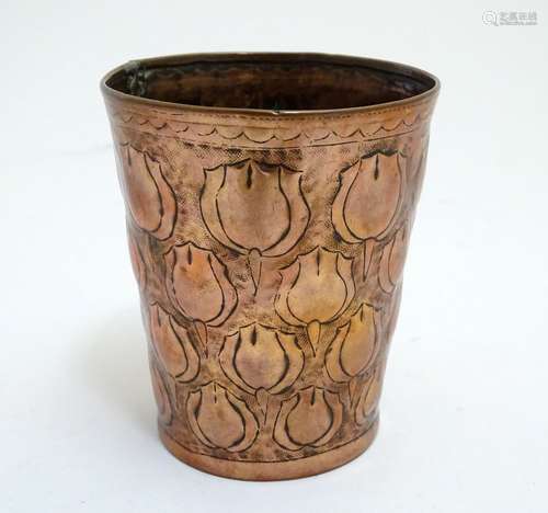 An Arts and Crafts copper beaker of tapering form with repousse floral decoration in the manner of