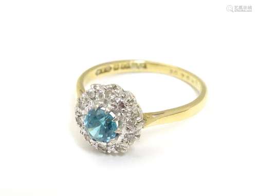 An 18ct gold ring set with central blue zircon bordered by diamonds. Ring size approx. M 1/2