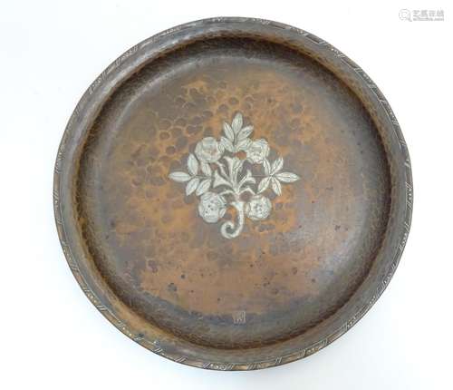 A Hugh Wallis Arts and Crafts hammered copper charger of circular form with silver plate floral