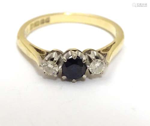 An 18ct ring set with dark blue spinel flanked by diamonds. Ring size approx I Please Note - we do