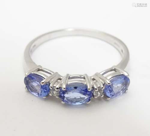 A 9ct white gold ring set with three tanzanite and two diamonds in a linear setting, Ring size