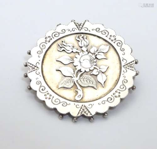 A Victorian silver brooch of circular form with floral detail. Hallmarked Birmingham 1890 maker