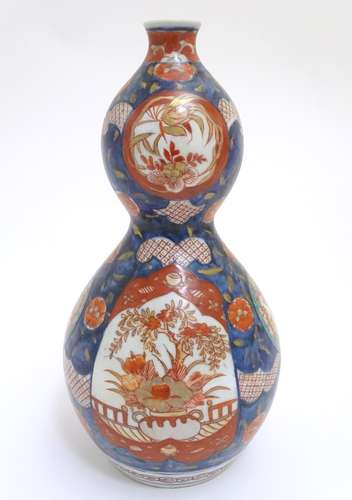 An Oriental double gourd vase in the Imari palette with lobed panels depicting plants on a