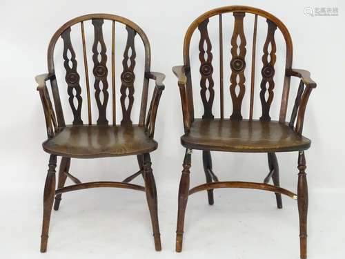 A pair of late 18thC yew wood Windsor chairs with draught back supports and shaped arms, the