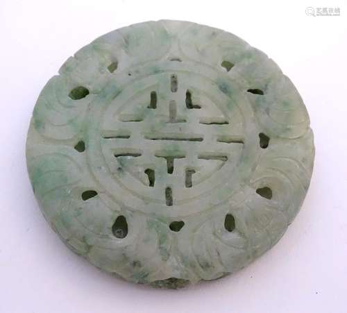 An Oriental jade roundel carving depicting a stylised dragon. Approx. 2 1/4